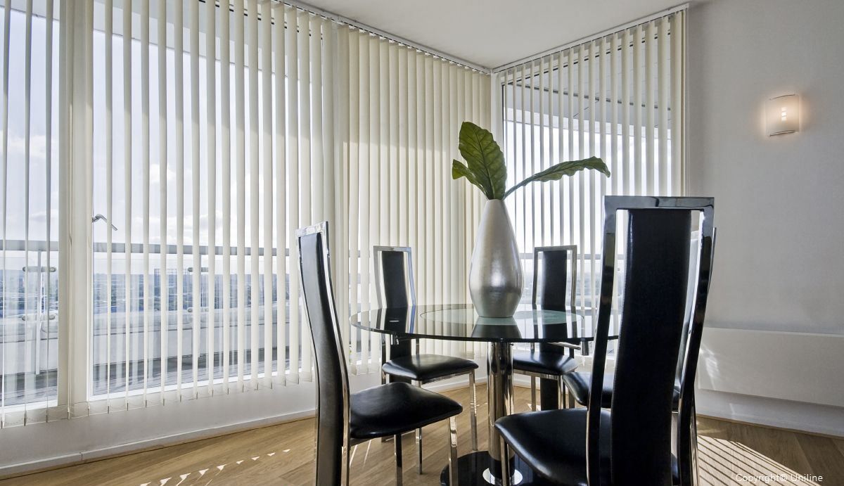 A Dining Room With A Table And Chairs And Vertical Blinds — Mid Coast Flooring & Blinds In Taree, NSW