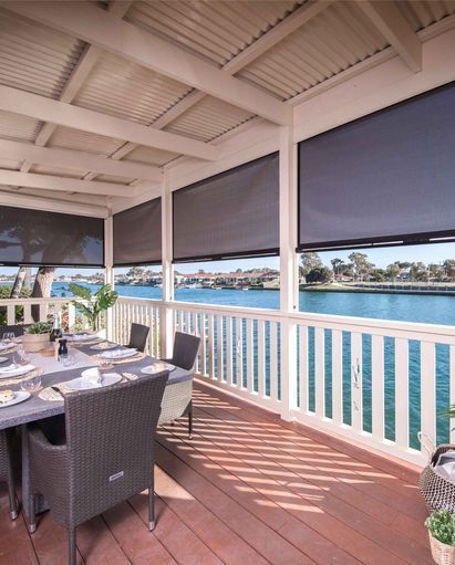 A Patio With A Table And Chairs Overlooking A Body Of Water — Mid Coast Flooring & Blinds In Taree, NSW