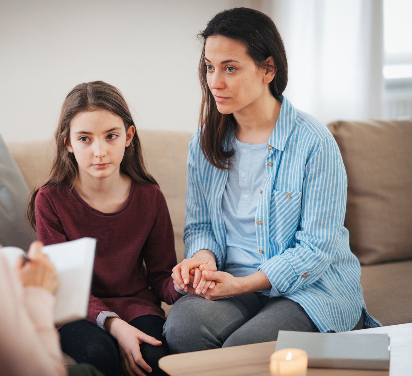 Una madre e una figlia sono sedute su un divano e parlano con uno psicologo.