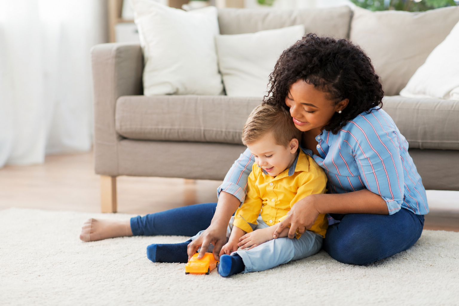 Woman and young child stacking colorful blocks on a couch
