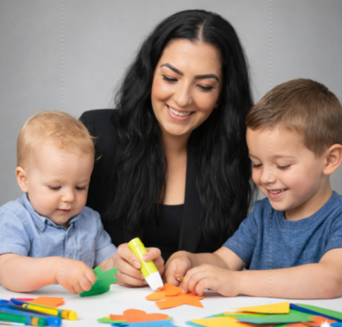 Three people smiling and making paper crafts with colorful paper and glue at a table
