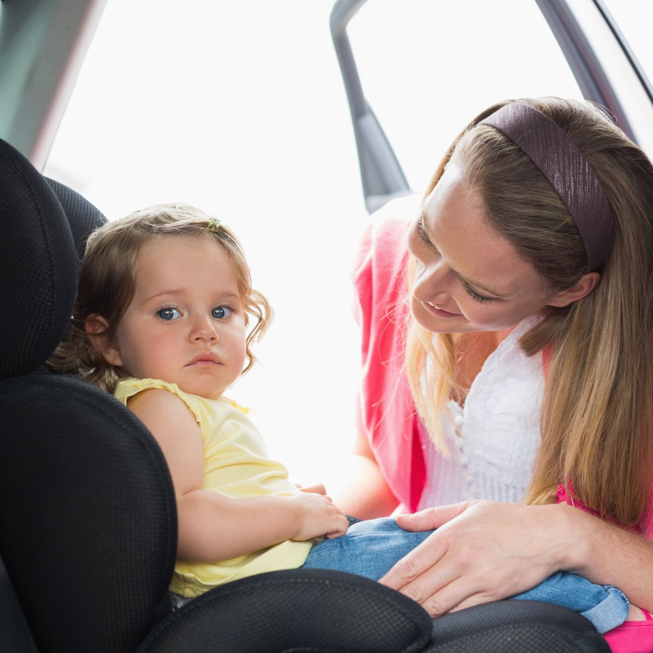 Woman smiling at a child in a car seat inside a vehicle