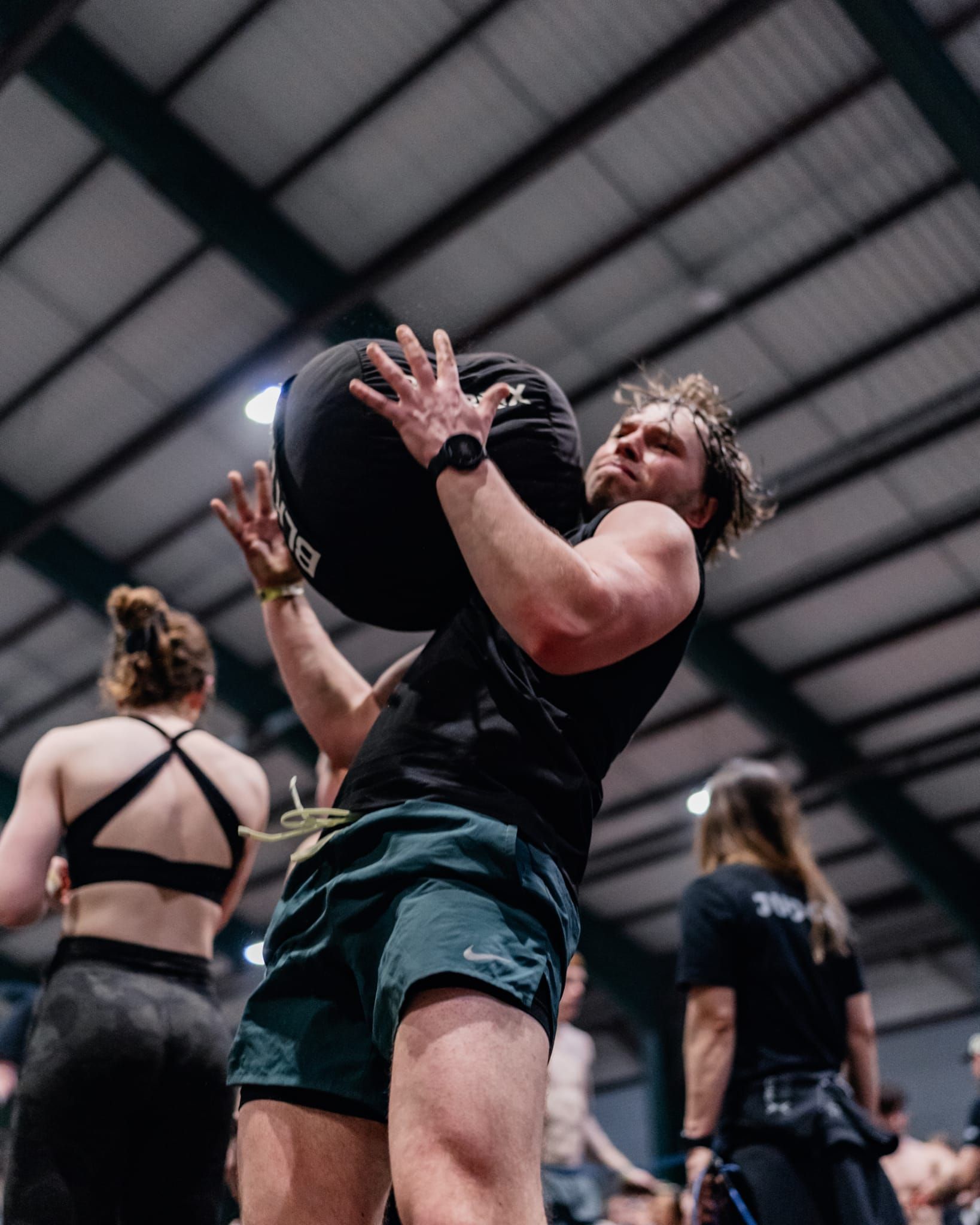 A man is squatting down with a kettlebell in his hands.