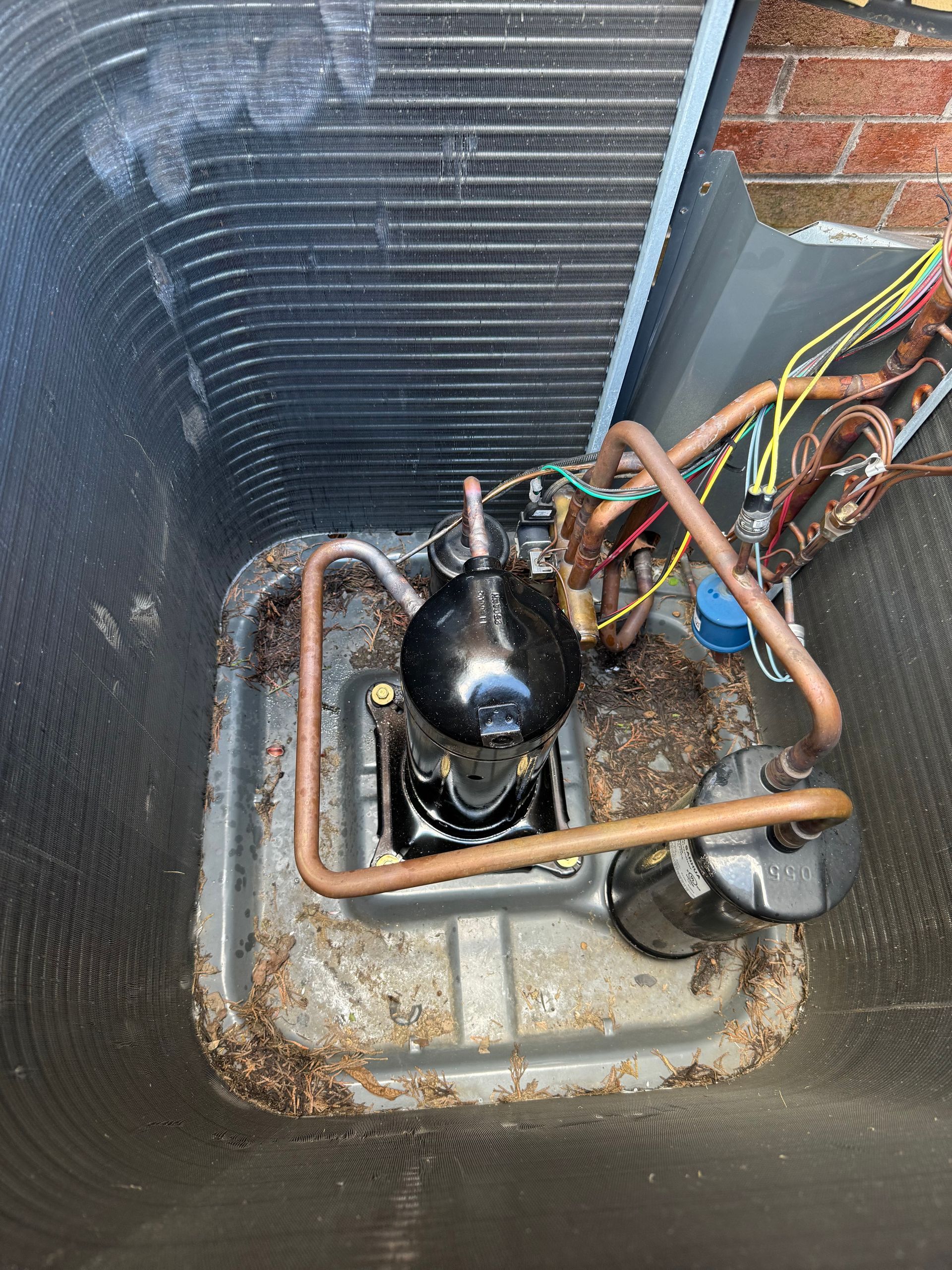 A close up of a dirty air conditioner with copper pipes coming out of it.