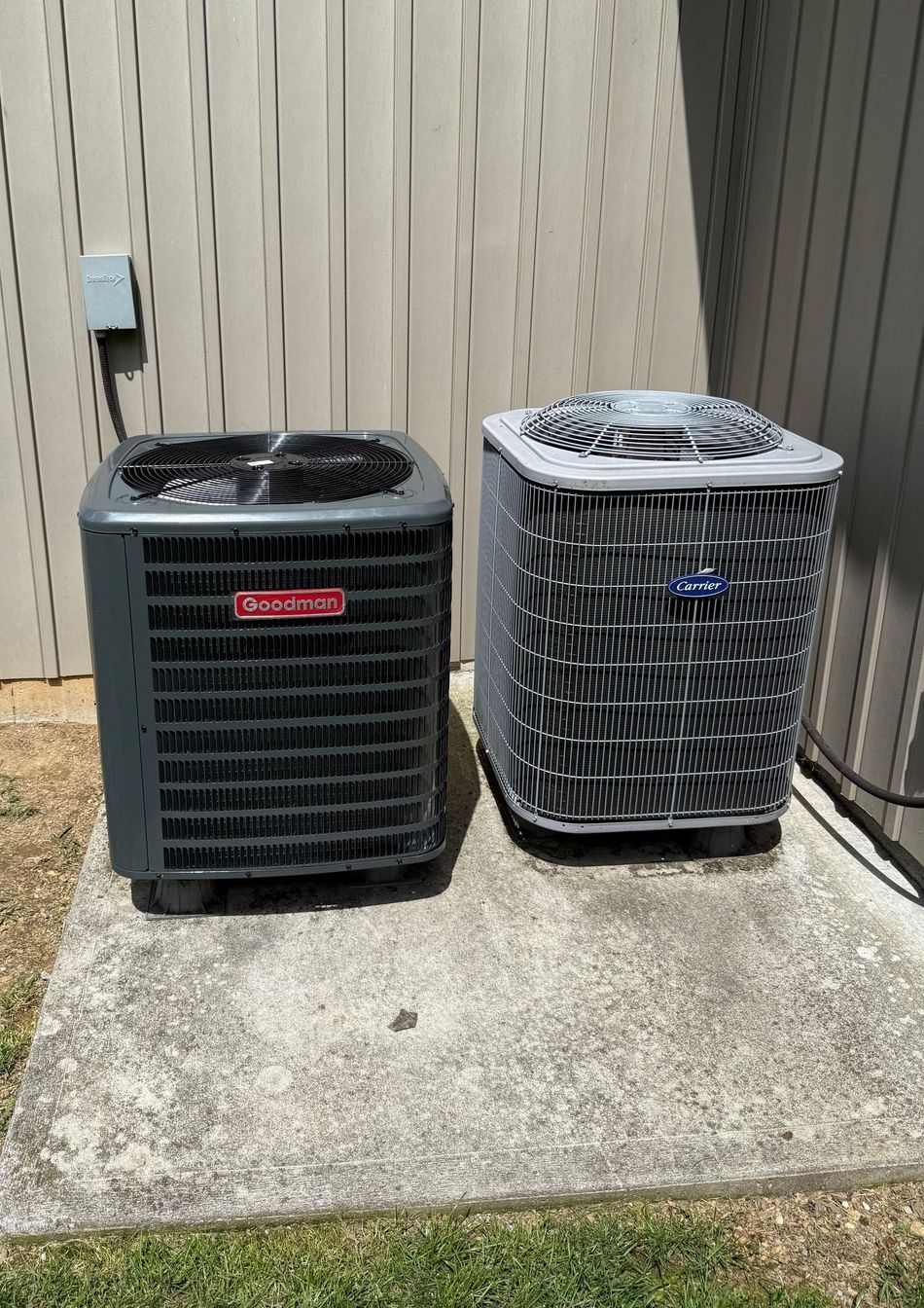 Two air conditioners are sitting next to each other on a sidewalk.