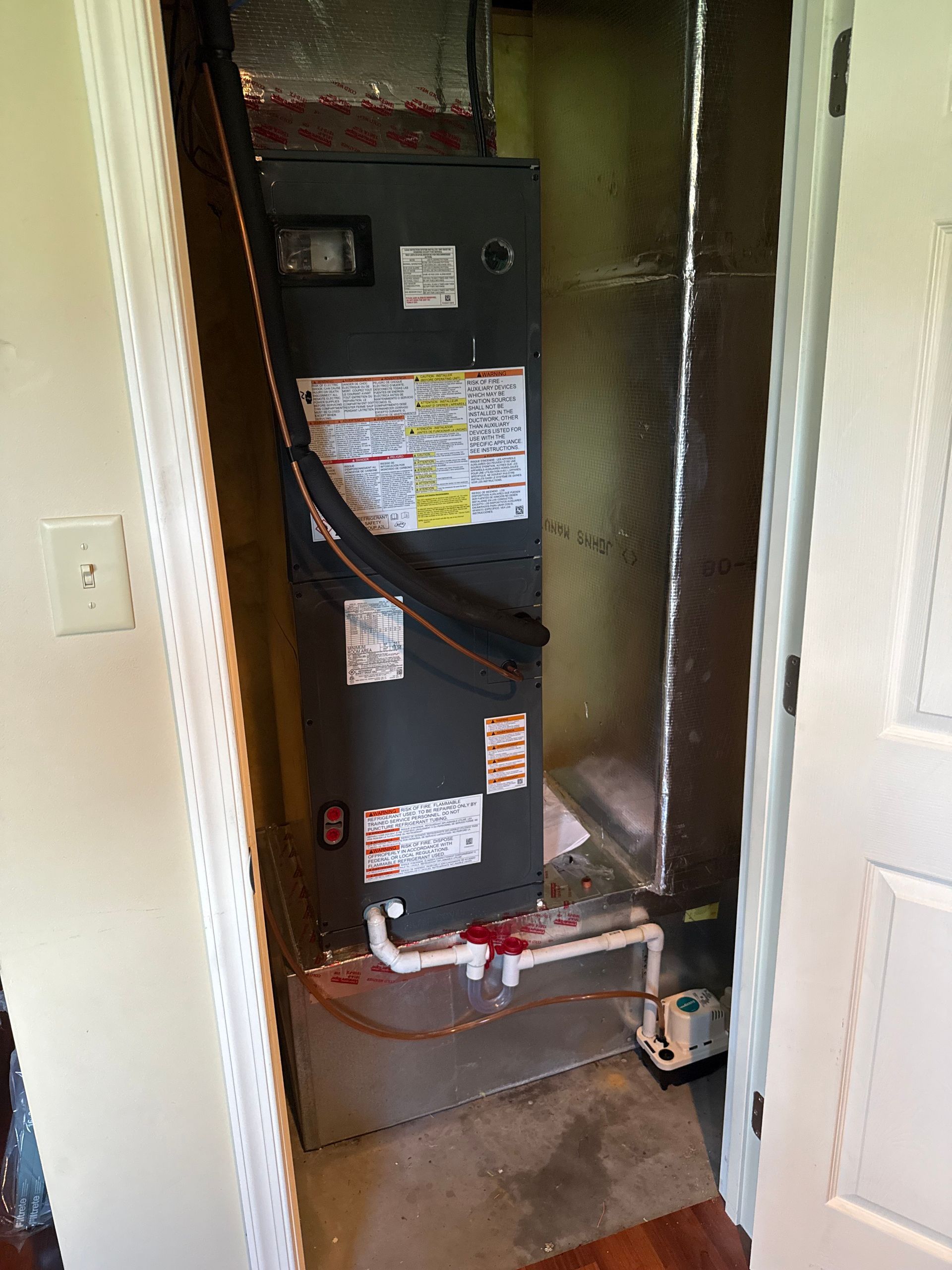 An air conditioner is sitting in a closet next to a door.