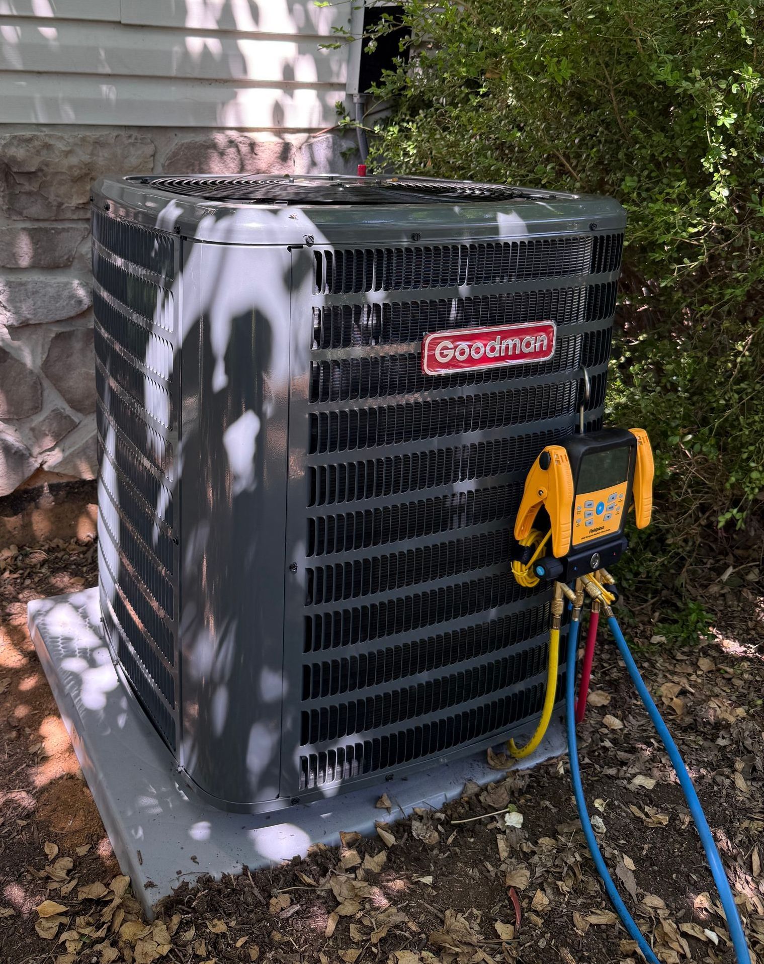 An air conditioner is sitting outside of a house with a hose attached to it.