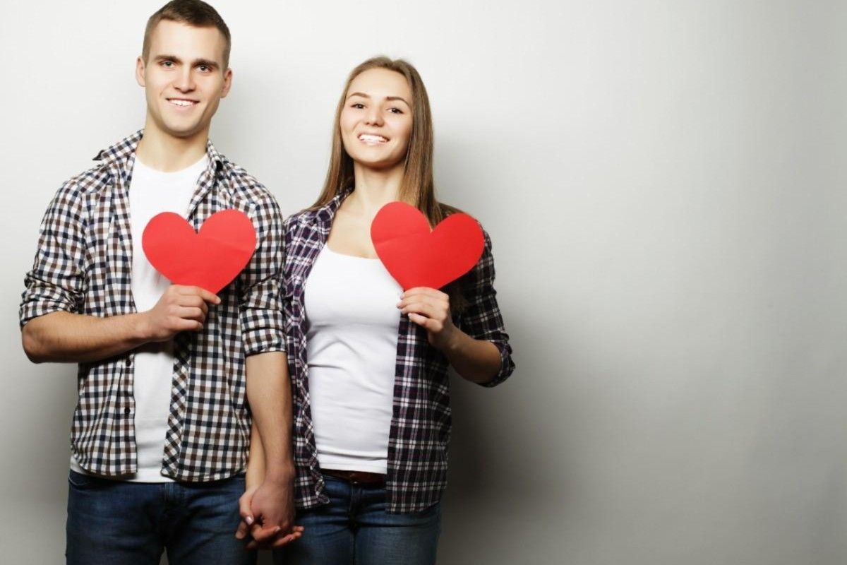 couple holding each other hands and holding hearts