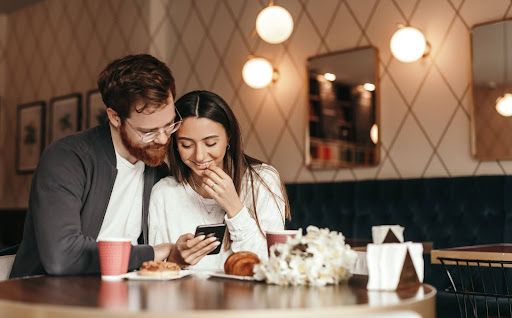 couples laughing at each other seeing mobile phone