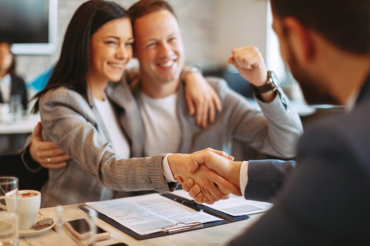 couple smiling and girl shaking hand with a professional