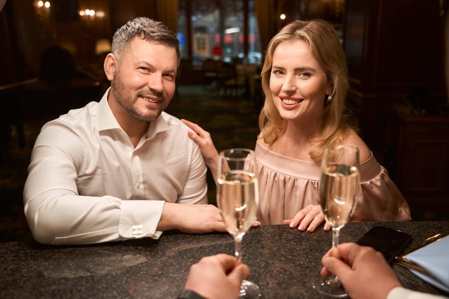 couples enjoying wine smilling towards the camera
