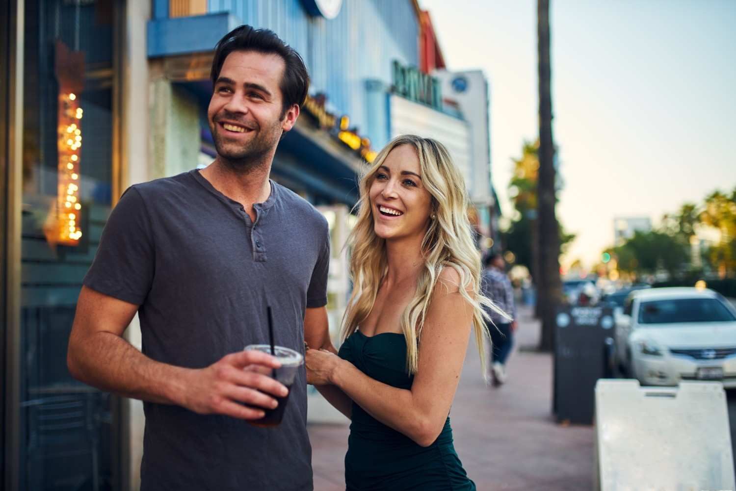 Happy couple laughing together while walking through a lively urban area on a date