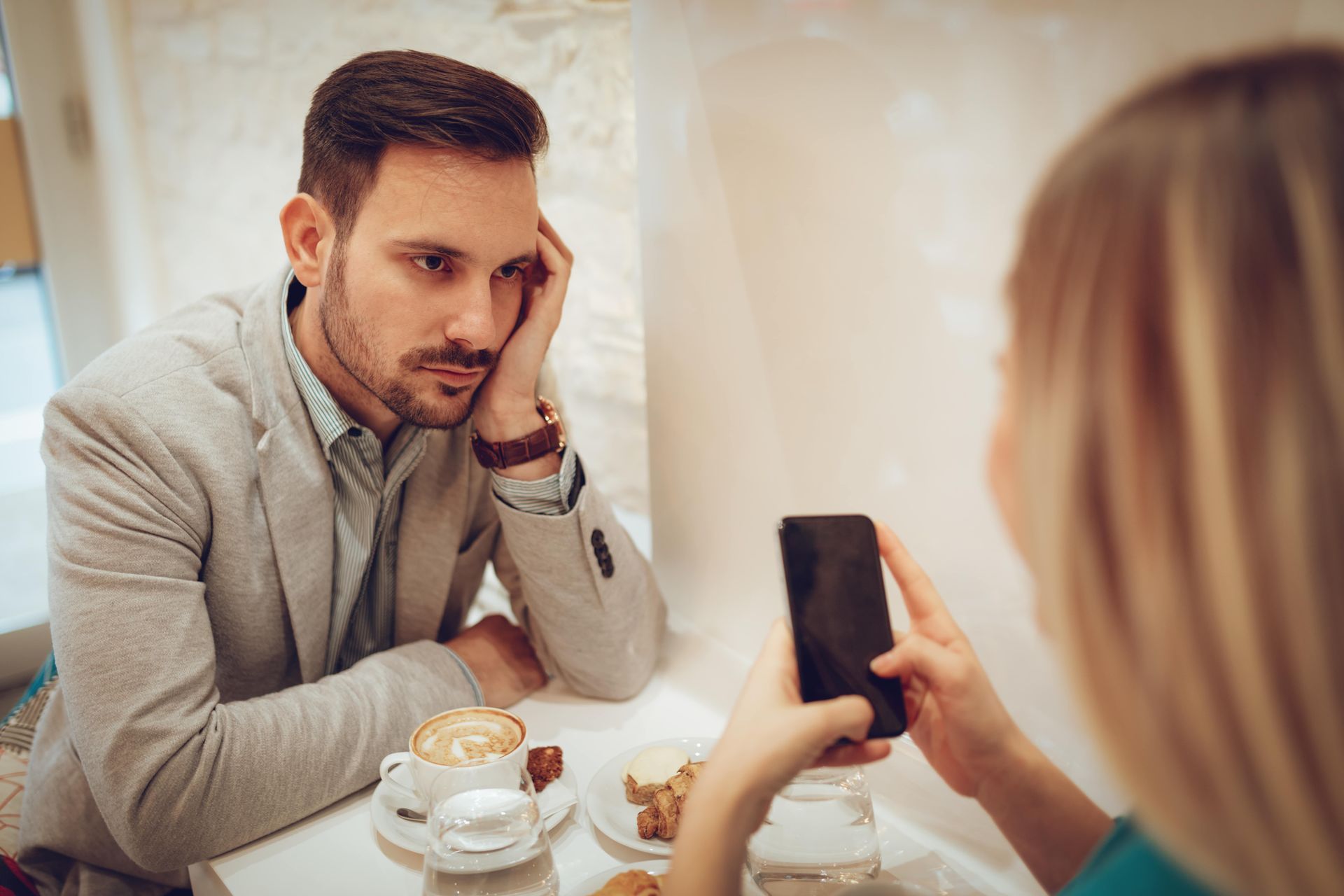 girl sitting with mobile boy looking towards her face