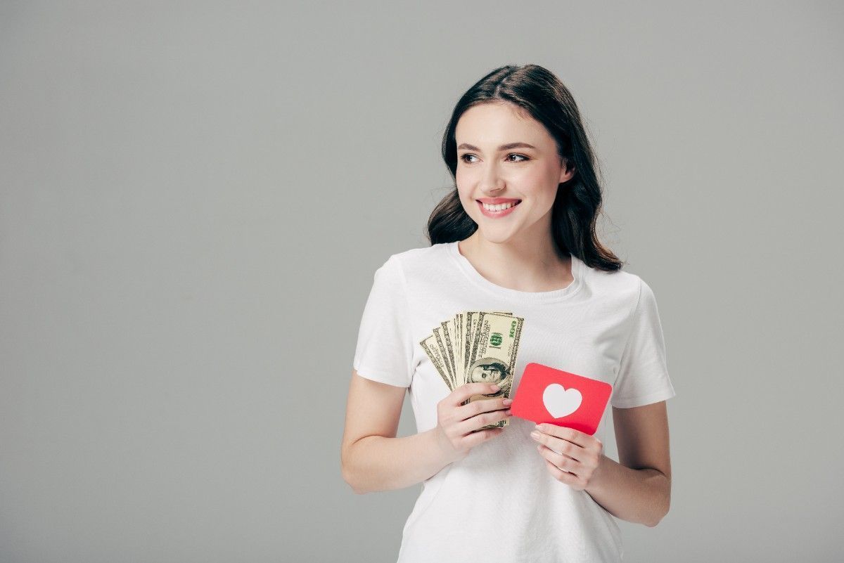 girl smiling holding money and a heart letter