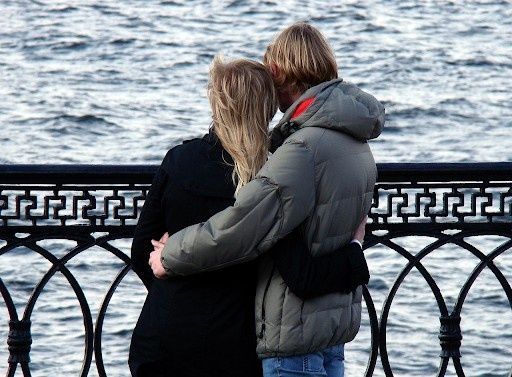 couples standing near sea hugging each other