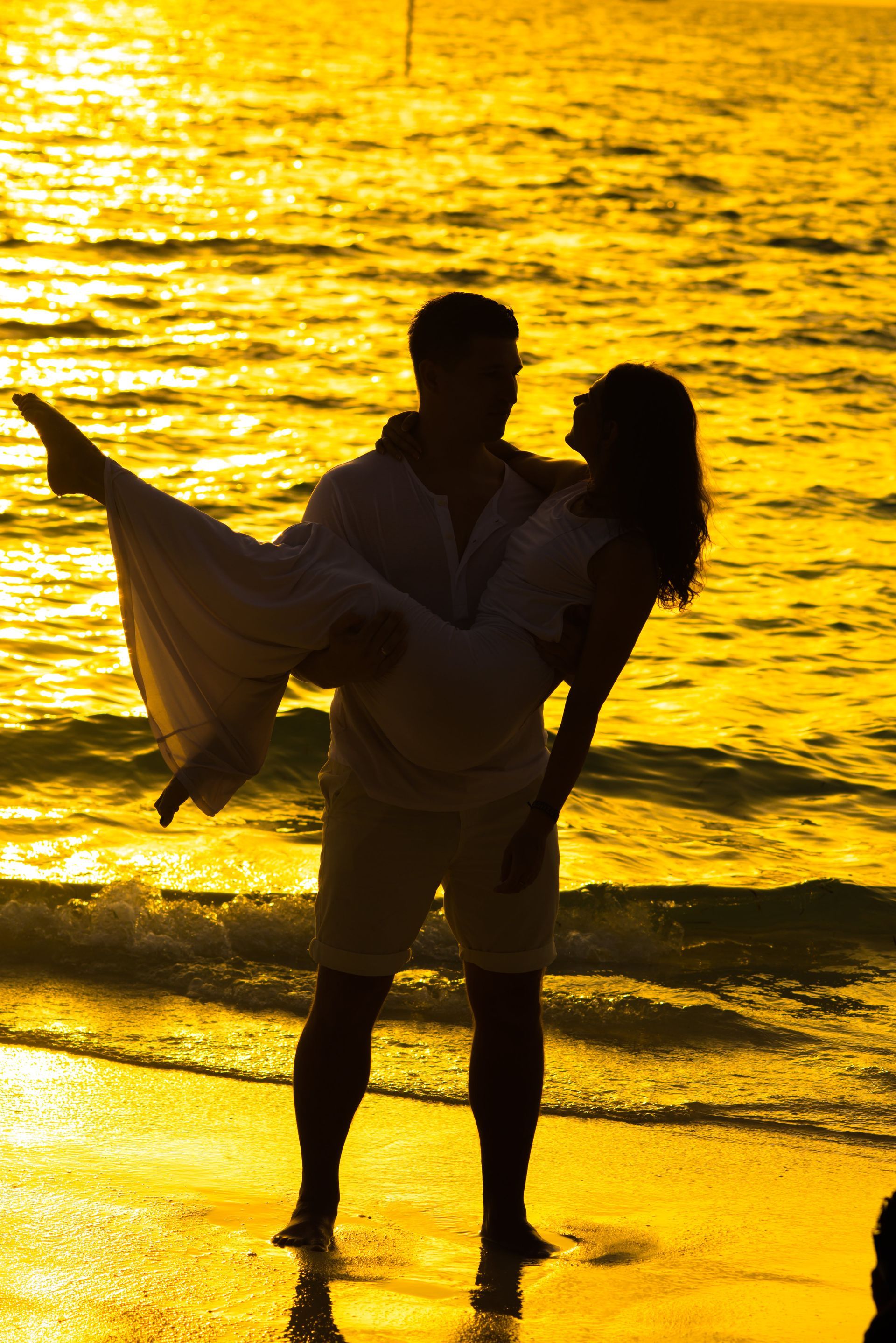 Man carrying woman in his arms at the beach during sunset, showcasing romance found through private matchmaking.