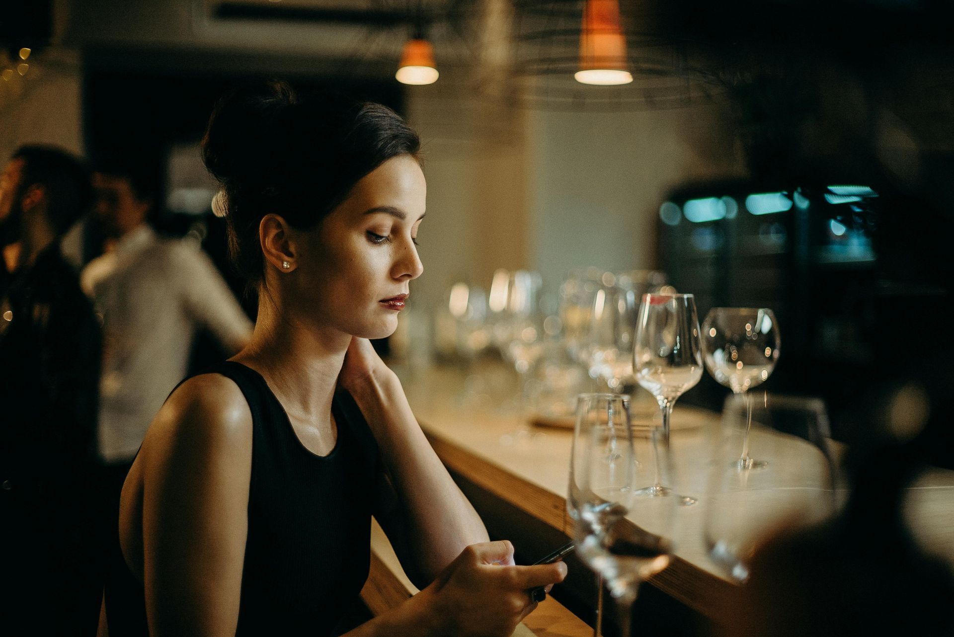 Successful woman at an elegant restaurant bar texting while exploring intentional dating