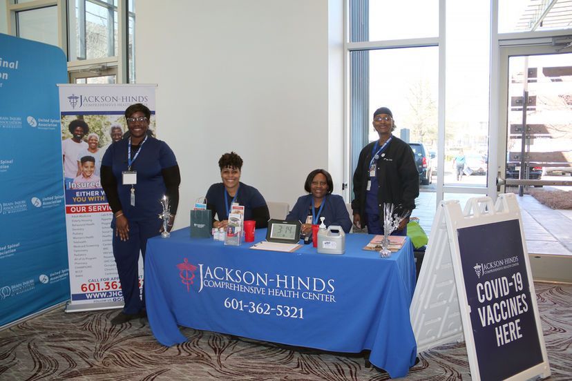 A group of people standing around a table with a blue table cloth.