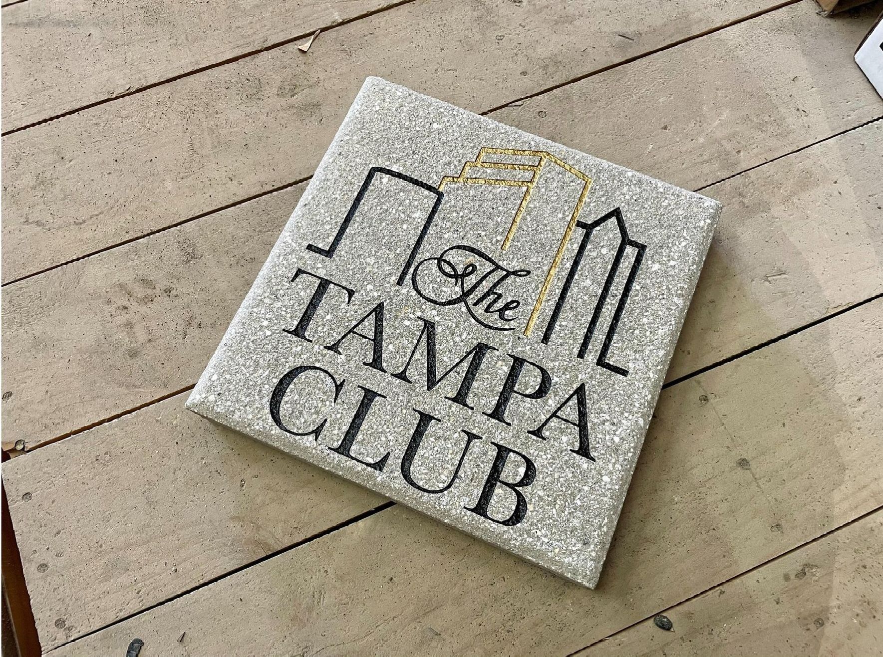 A sign for the tampa club is sitting on a wooden floor.