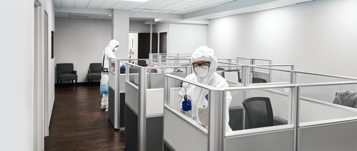 a man in a protective suit is standing in an office cubicle .