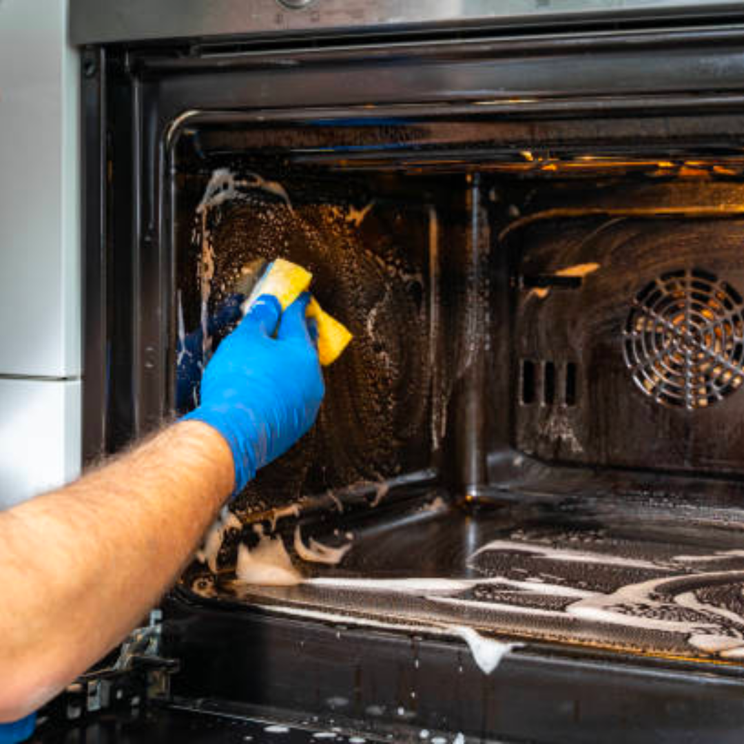 a person is cleaning an oven with a sponge