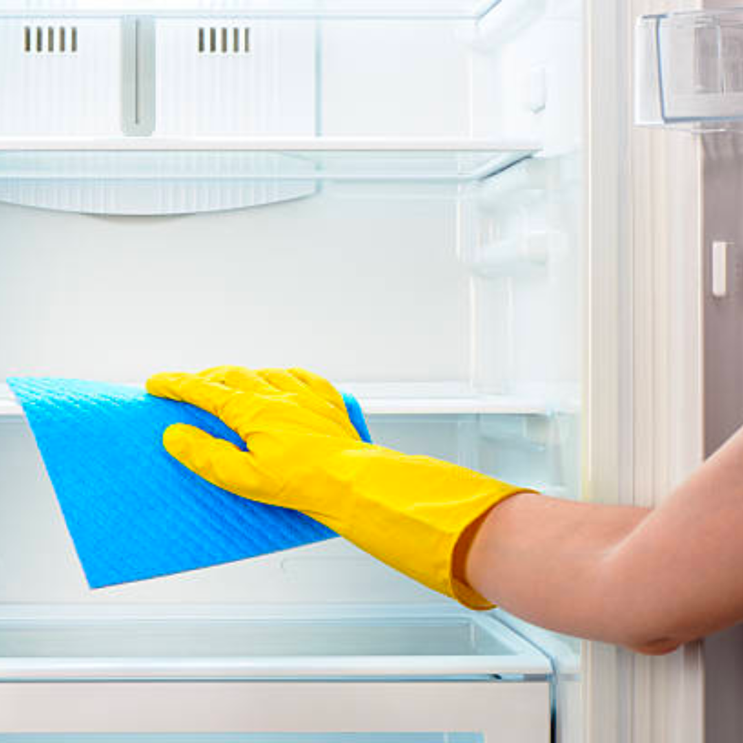 a person wearing yellow gloves is cleaning an empty refrigerator with a blue cloth