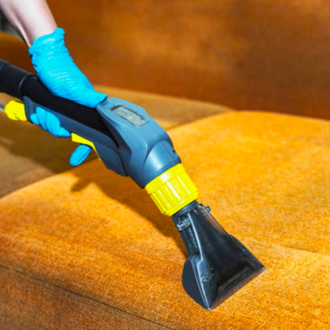 a person is cleaning a couch with a vacuum cleaner .