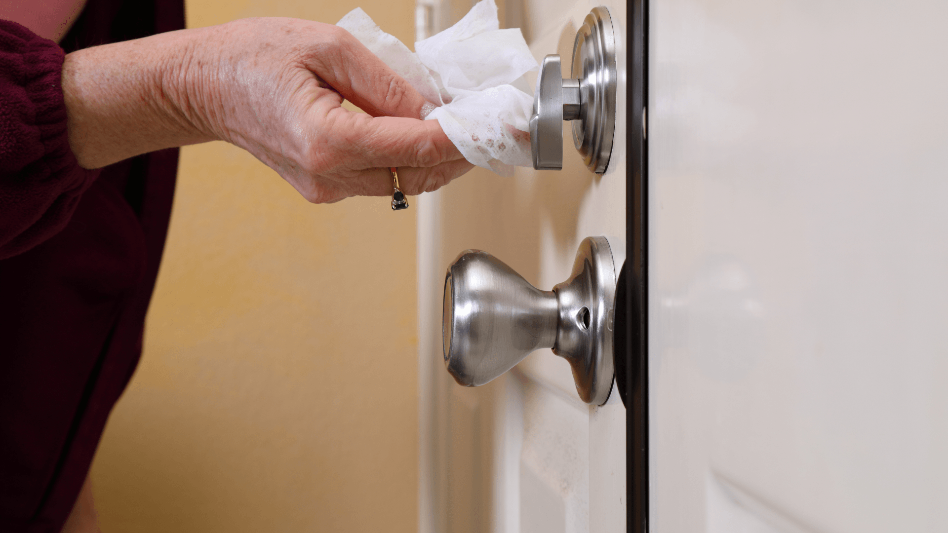 an elderly woman is cleaning a door handle with a tissue