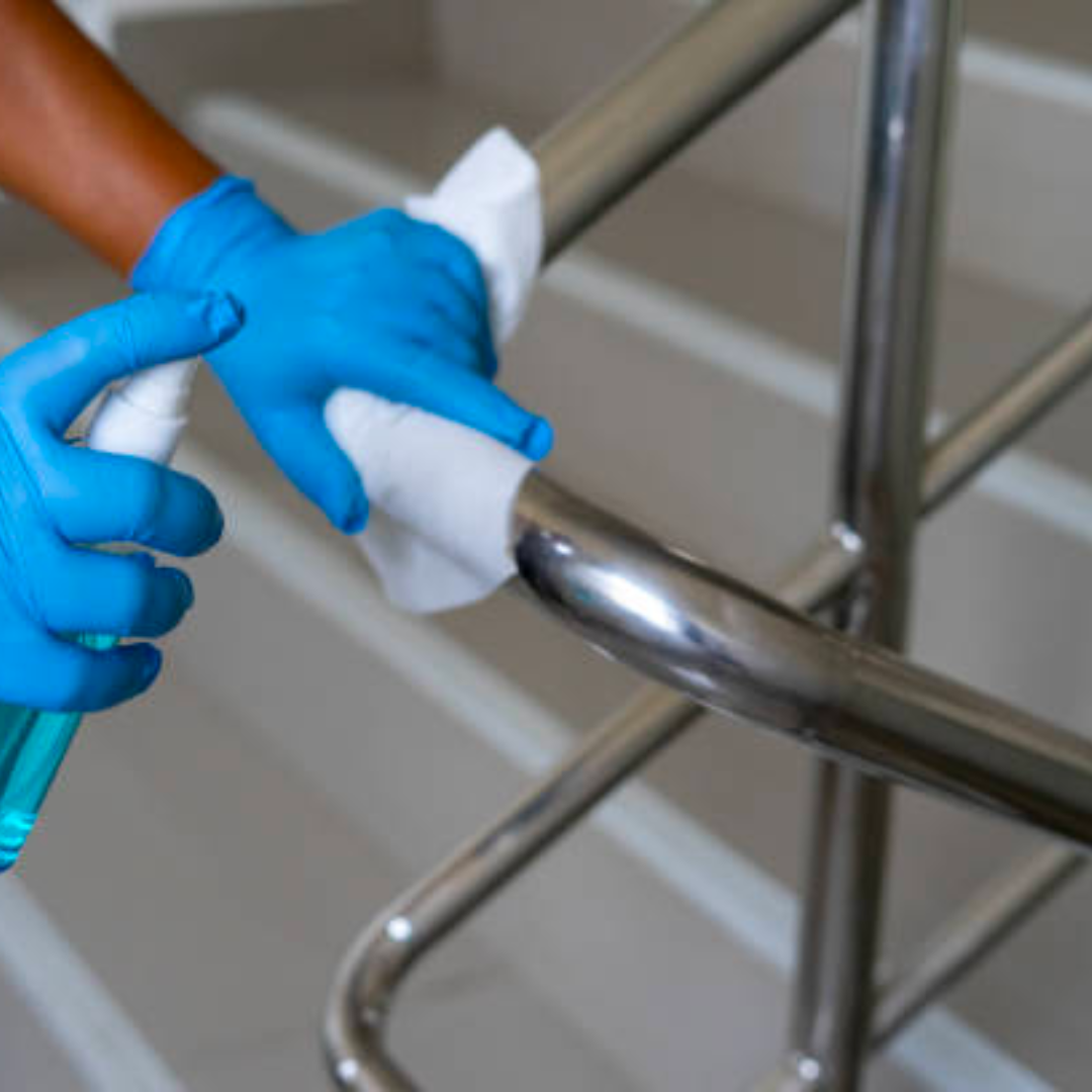 a person wearing blue gloves is cleaning a metal railing with a cloth
