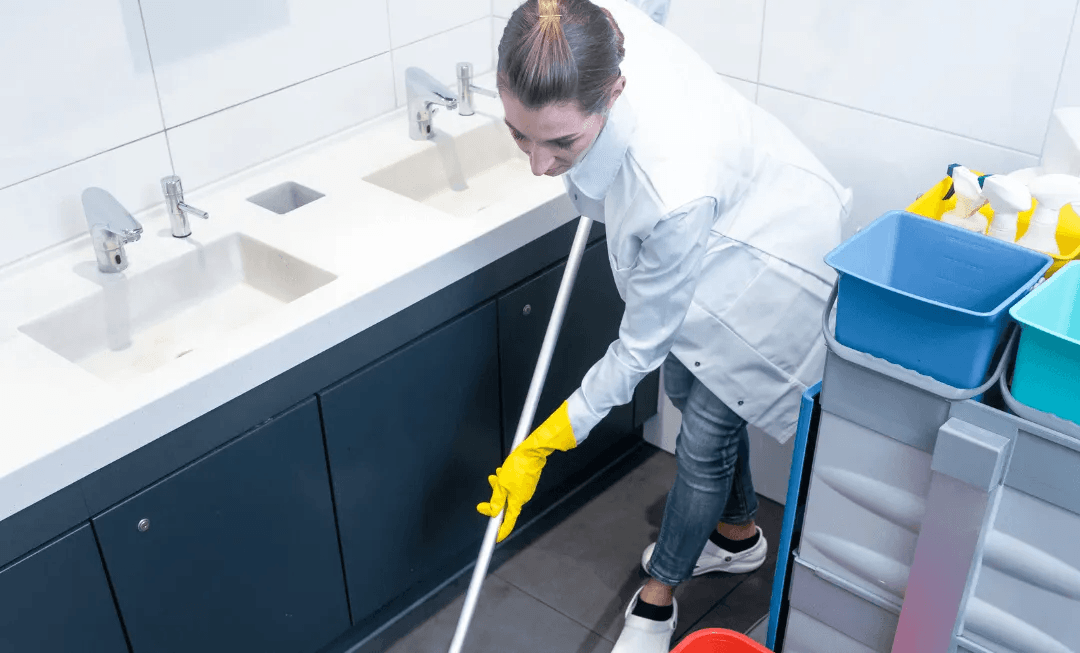 a woman is cleaning a bathroom floor with a mop