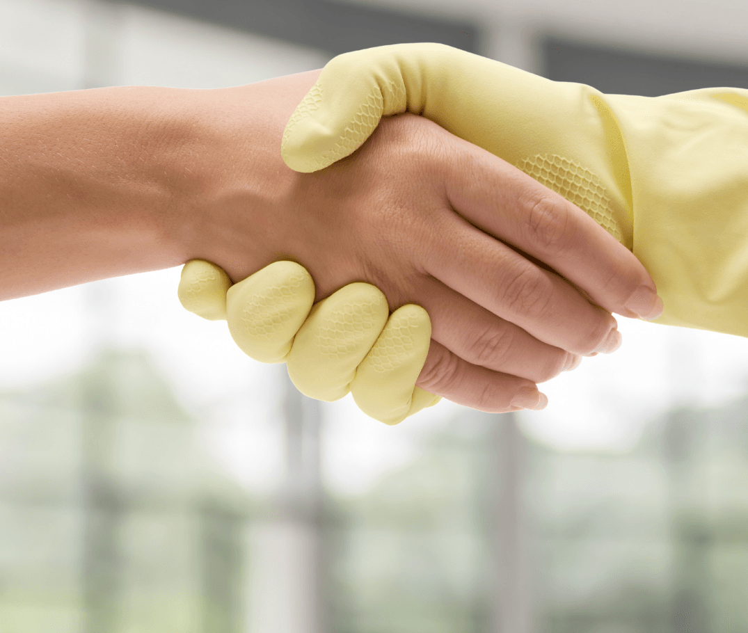 Two people wearing yellow rubber gloves shake hands