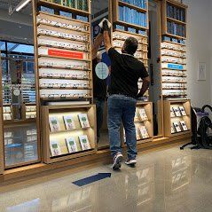 a man is standing in front of a wall of bookshelves in a library .
