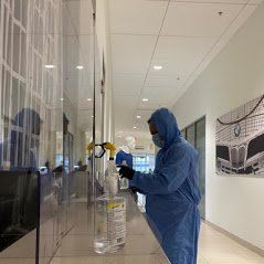 a man in a protective suit is spraying a wall in a hallway .