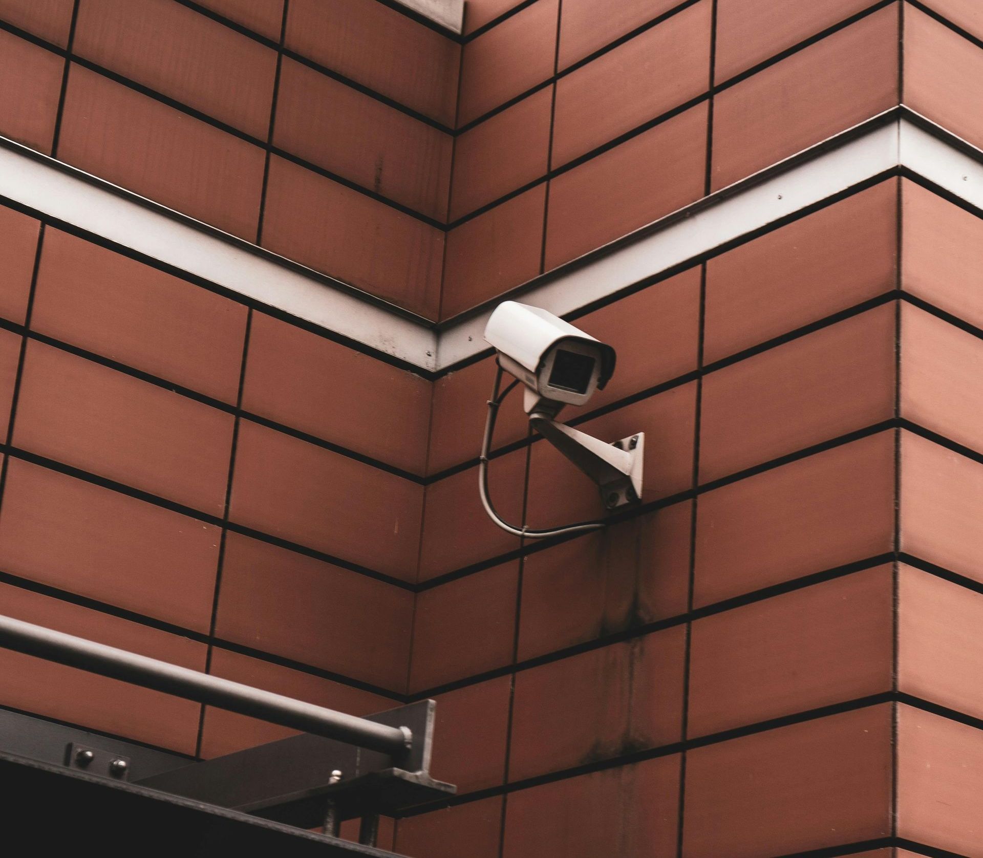 A security camera is mounted on the side of a brick building.