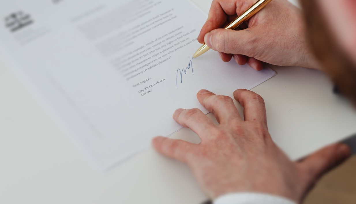 a man is signing a document with a pen 