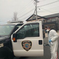 a man in a protective suit is spraying a truck with a hose .
