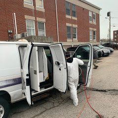 a man in a protective suit is getting out of a van .