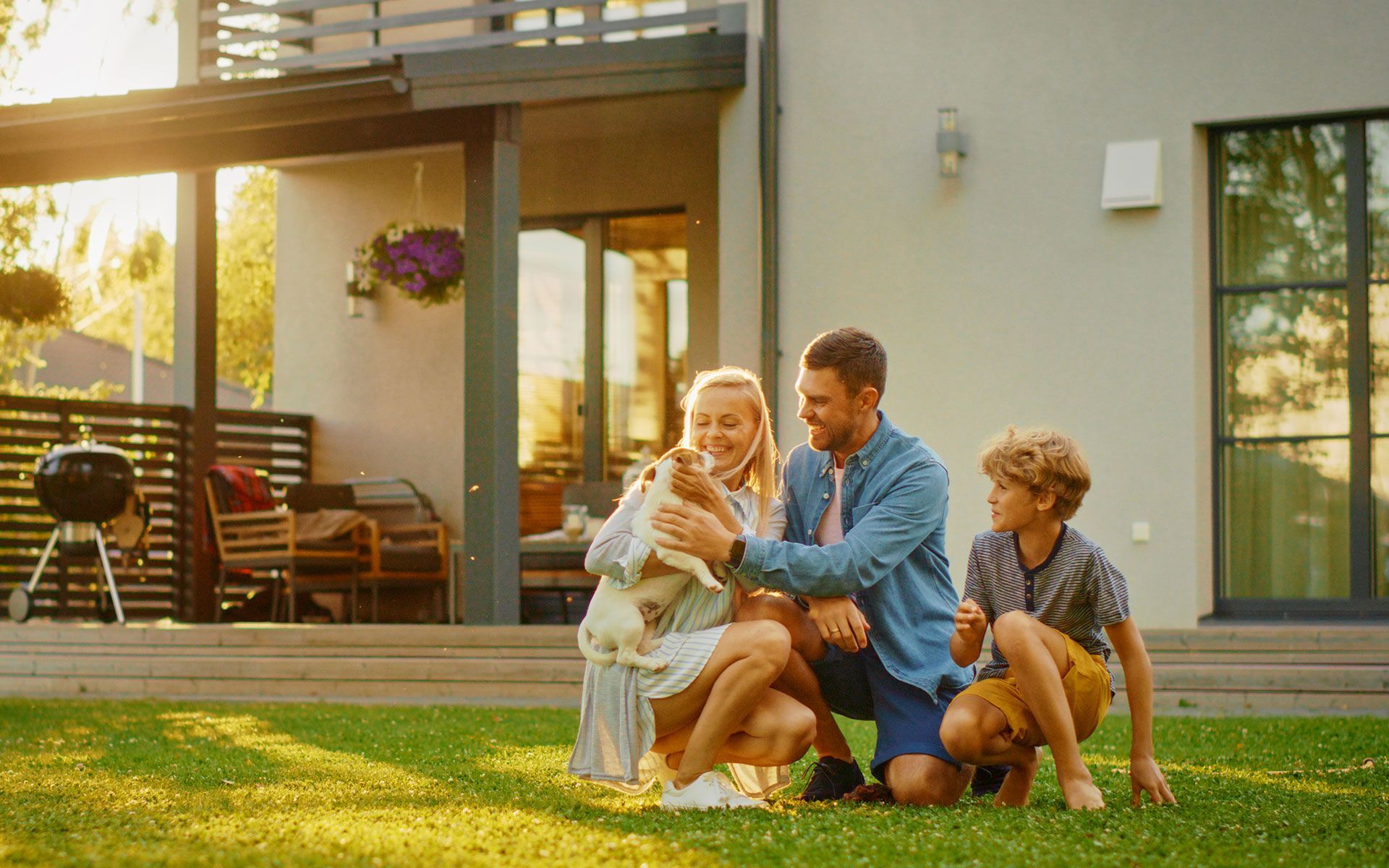 Family petting a small dog in their backyard on a sunny day.