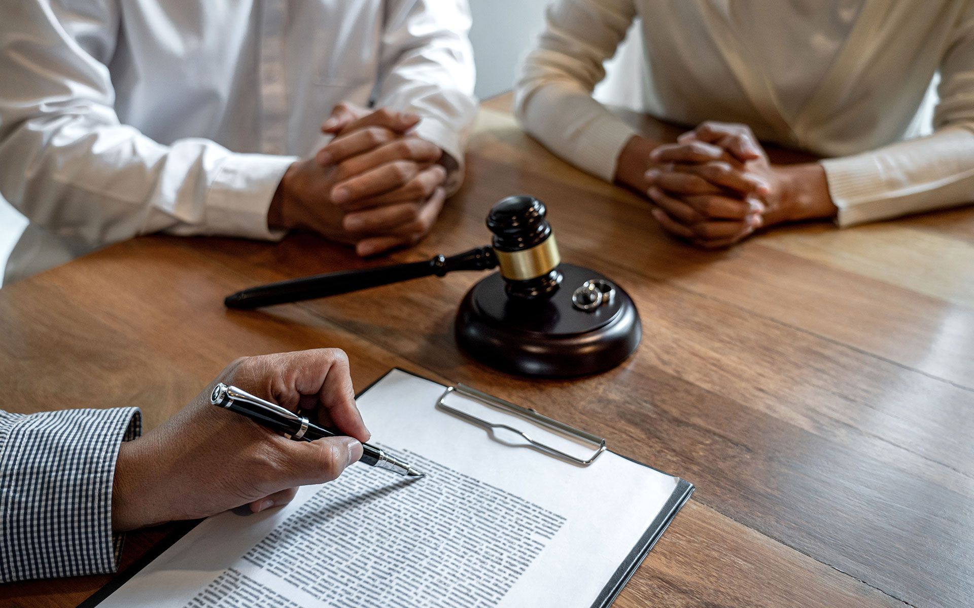 A couple at a table with a gavel and papers, likely discussing divorce with a lawyer.