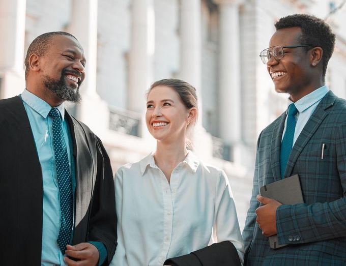 A group of people are standing next to each other in front of a building and smiling.