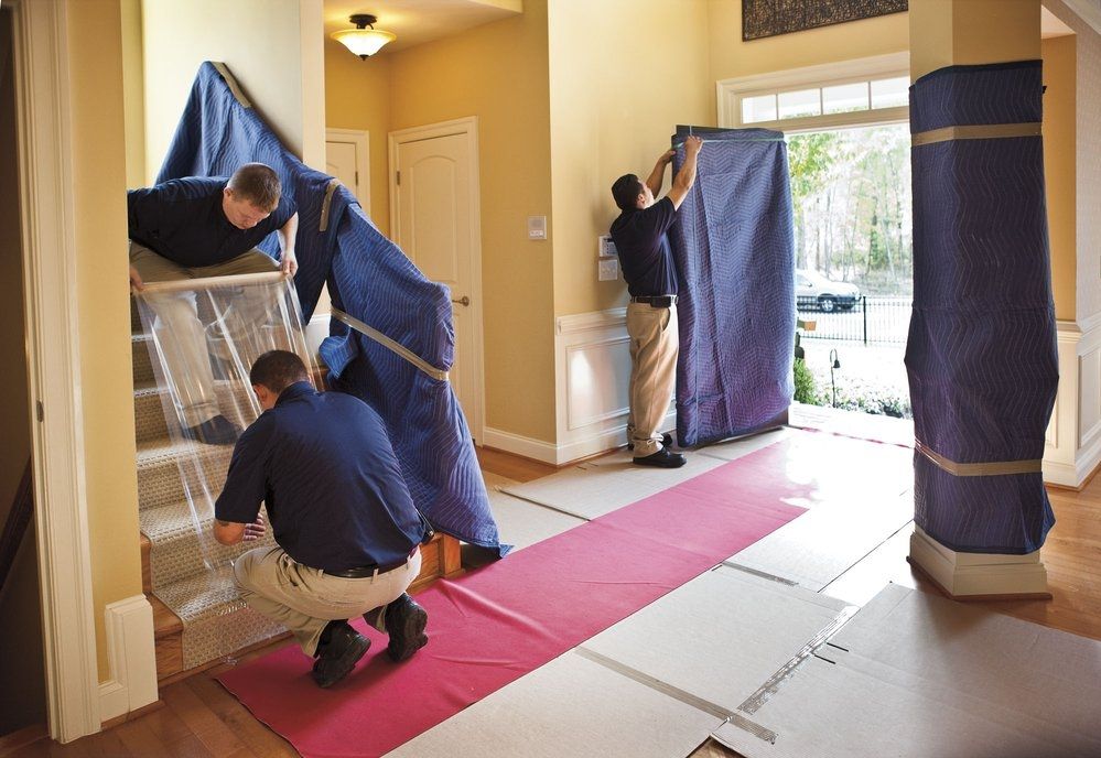 Two men are moving a couch in a living room.