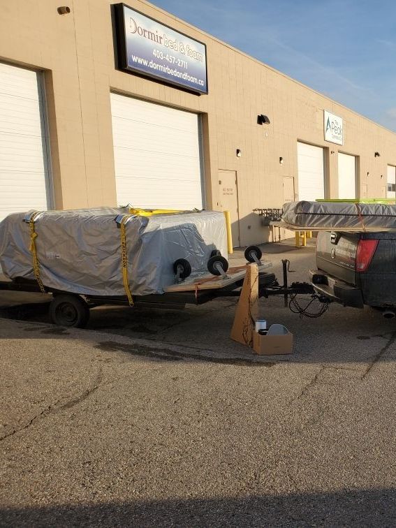 Two delivery men are carrying boxes and one is holding a clipboard.