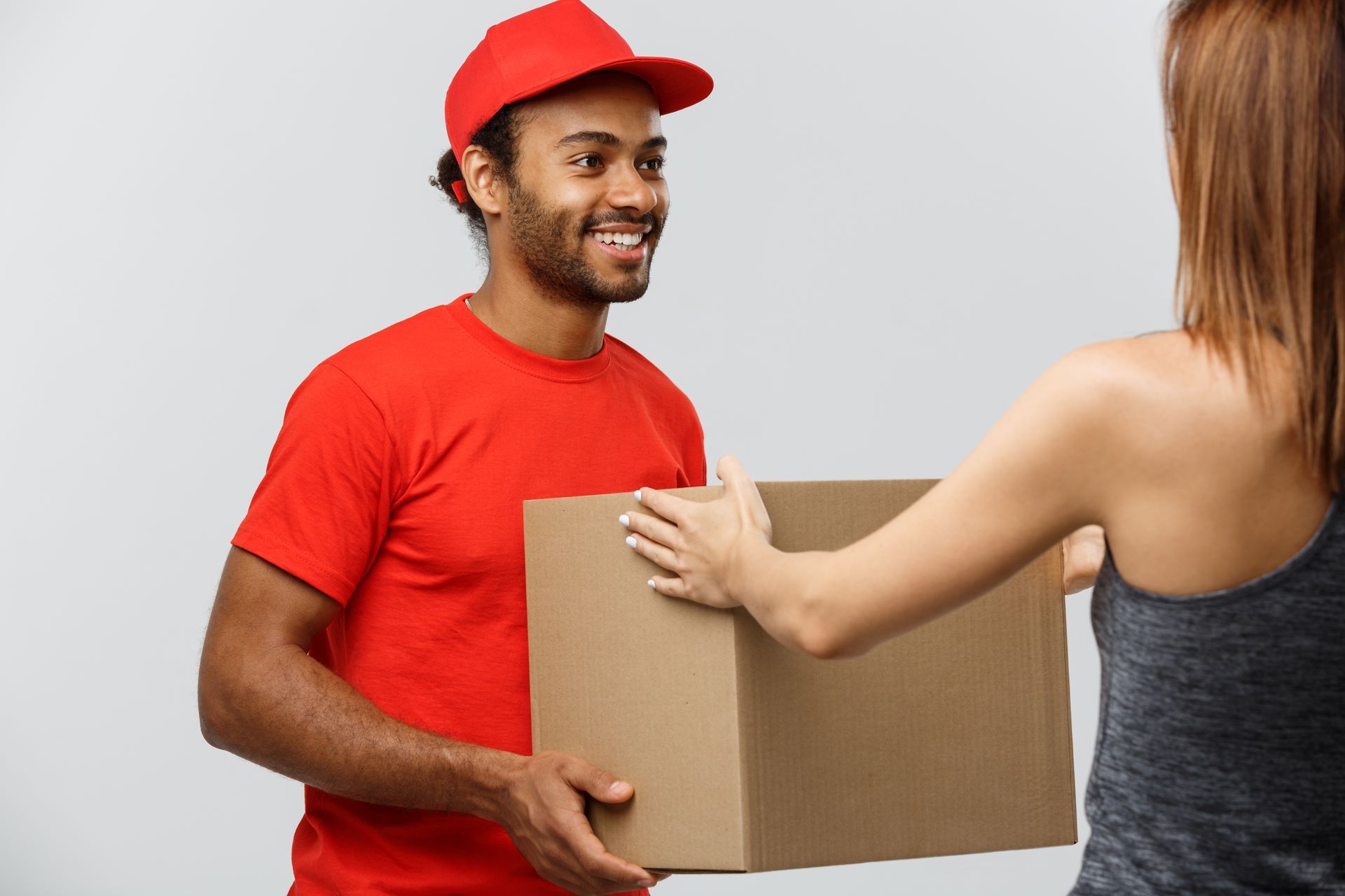 A delivery man is giving a box to a woman.