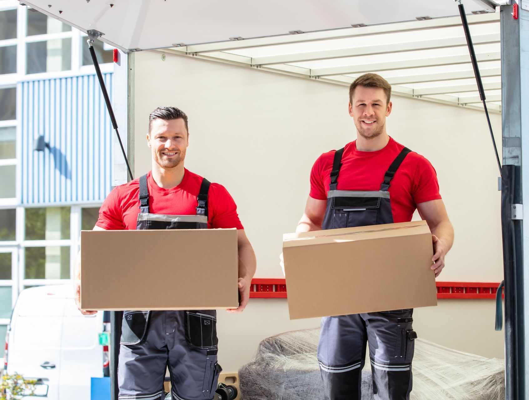 Two men are carrying boxes out of a moving truck.