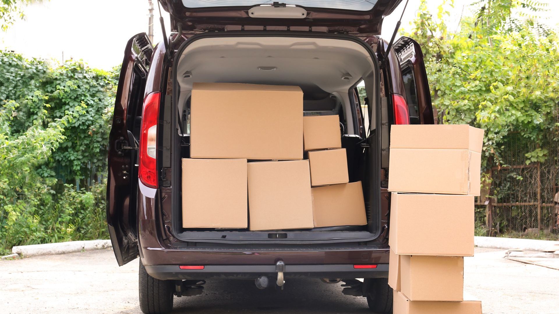 Two delivery men are carrying boxes into a van.