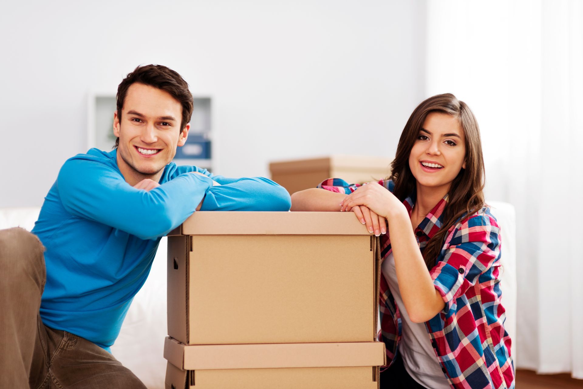 A man and a woman are leaning on a pile of cardboard boxes.