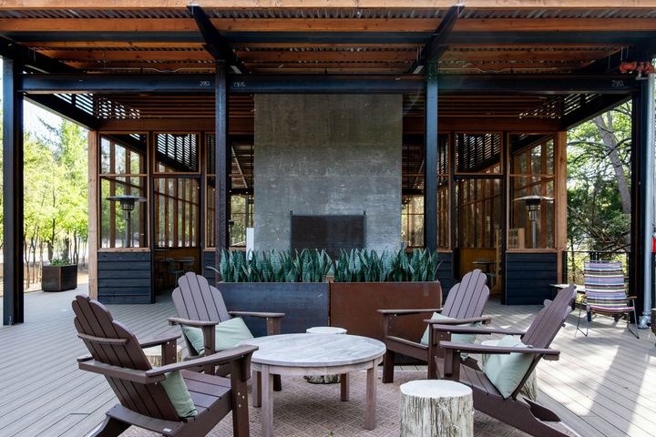 Outdoor patio with wooden chairs around a fire pit under a covered pavilion