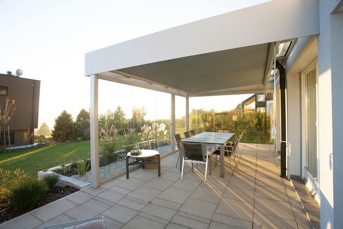 Modern patio with pergola, outdoor table and chairs, and sunset light in a landscaped backyard
