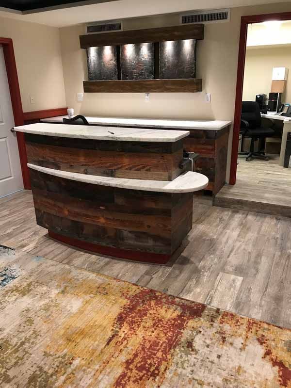 A wooden reception desk in a room with a rug.