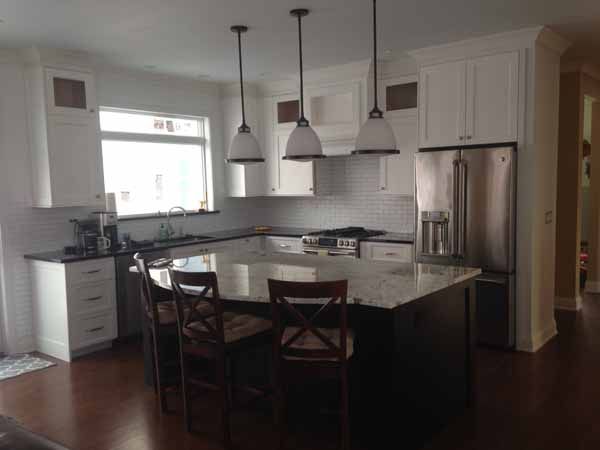 A kitchen with white cabinets , stainless steel appliances and a large island.
